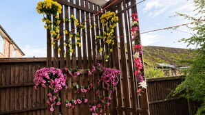 A wooden pergola with a lattice top, adorned with hanging flowers. - Newtons Lodge: Cosy 3-Bed Home, Cul-de-Sac, Free Parking, NTU & QMC Nearby (Nottingham)