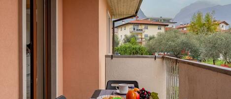 A balcony with a table set for breakfast, including bread, fruit, and beverages.