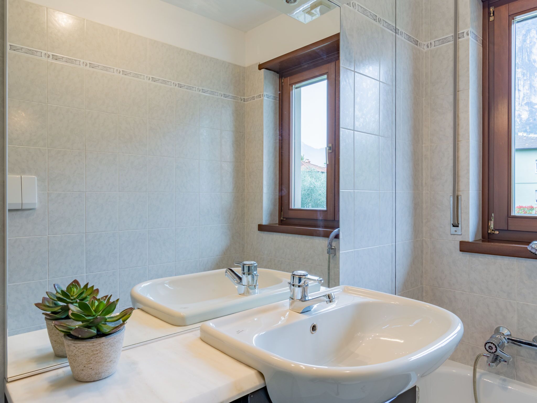 Un baño con dos lavamanos, una ventana y una planta en maceta.