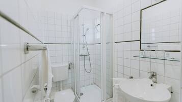 A modern bathroom with a glass-enclosed shower, a white sink, and a toilet.