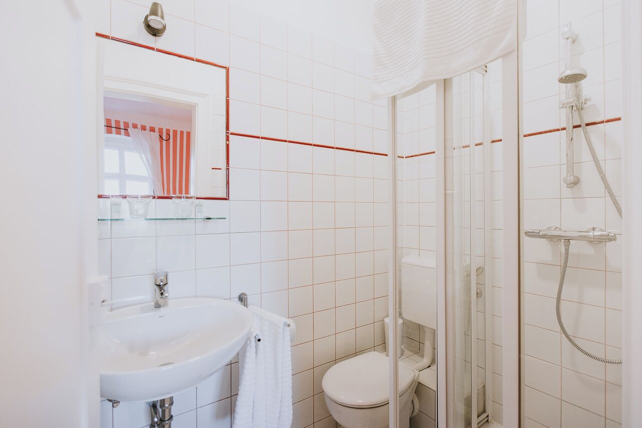 Une salle de bain moderne avec un lavabo blanc, des toilettes et une douche à parois de verre.