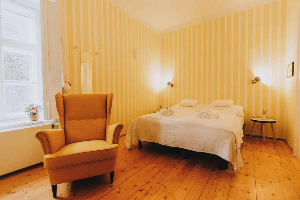 Una habitación con una cama, una silla y una mesita.