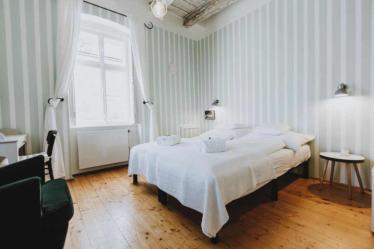 Un dormitorio con una cama, una silla, una mesa y una ventana con cortinas.