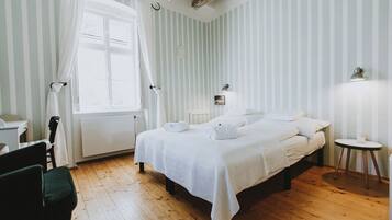 Un dormitorio con una cama, una silla, una mesa y una ventana con cortinas.