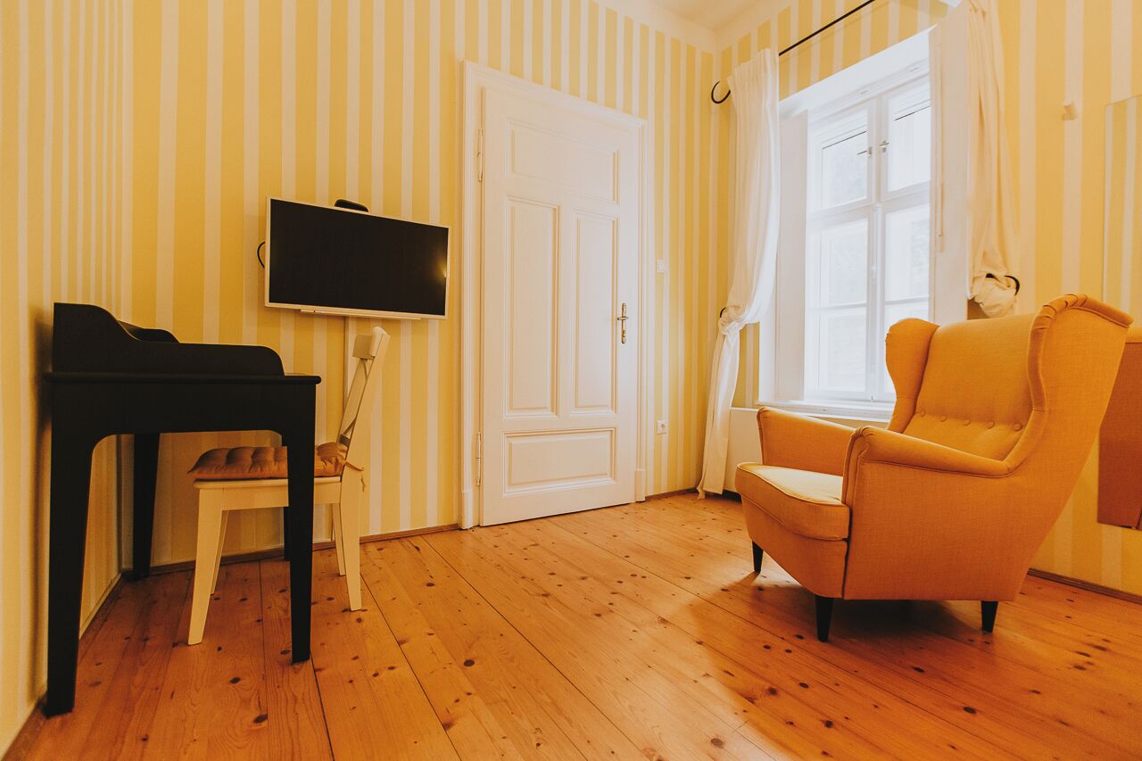 A room with a piano, a television, a chair, and a door.