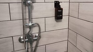 Una ducha con cabezal de ducha manual y panel de control en la pared.