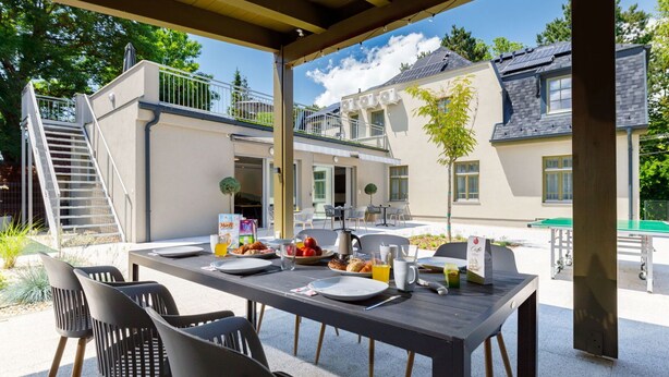 An outdoor dining area with a table set for four, surrounded by chairs, and a staircase leading to an upper level. - Beautiful apartment in villa for 12 people with WIFI, hot tub, A/C, TV and patio (Balatonfüred)