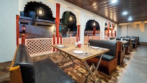 Un restaurante con mesas de madera y asientos de cuero negro, con decoración tradicional y vista a un edificio al fondo.