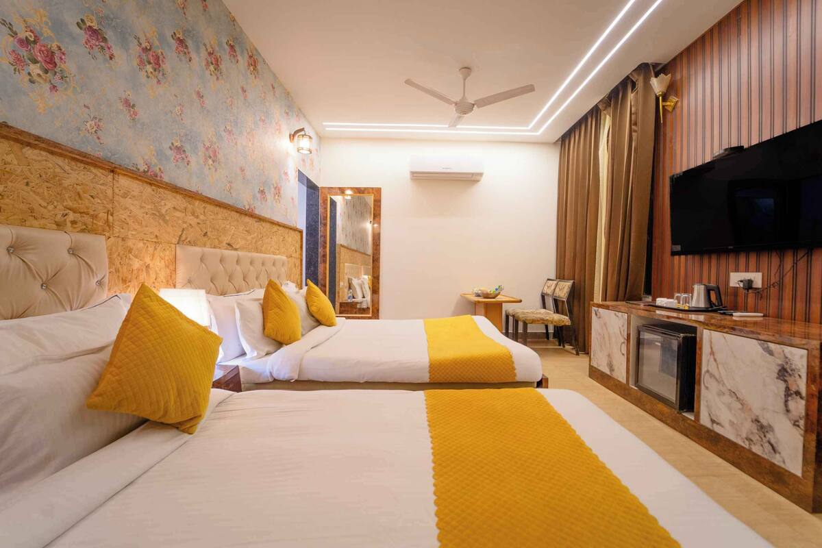 Een hotelkamer met twee bedden, een televisie, een bureau en een spiegel.