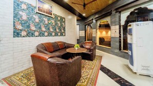 Cómoda zona de estar con sofás de cuero y una mesita, un muro decorativo con estampado floral y un letrero de restaurante a la vista.