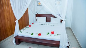 A bed with a canopy, a welcome mat, and a bedside table.