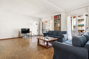 Una sala de estar con un sofá, una mesa de centro, un televisor y una estantería.