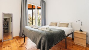 A bedroom with a bed, bedside table, and a mirror.