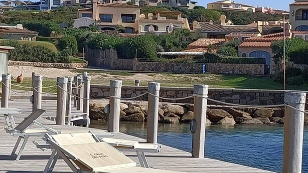 A wooden pier with sun loungers and a stone wall. - Porto Cervo Cala del Faro rent BILOCALE garden porch near the sea. (Porto Cervo)