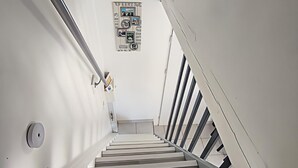 En moderne trappe med et minimalistisk design, et billede i en billedramme på væggen og et gelænder.