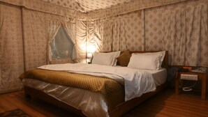 Un dormitorio con una cama grande, una mesita de noche con lámpara y cortinas estampadas.