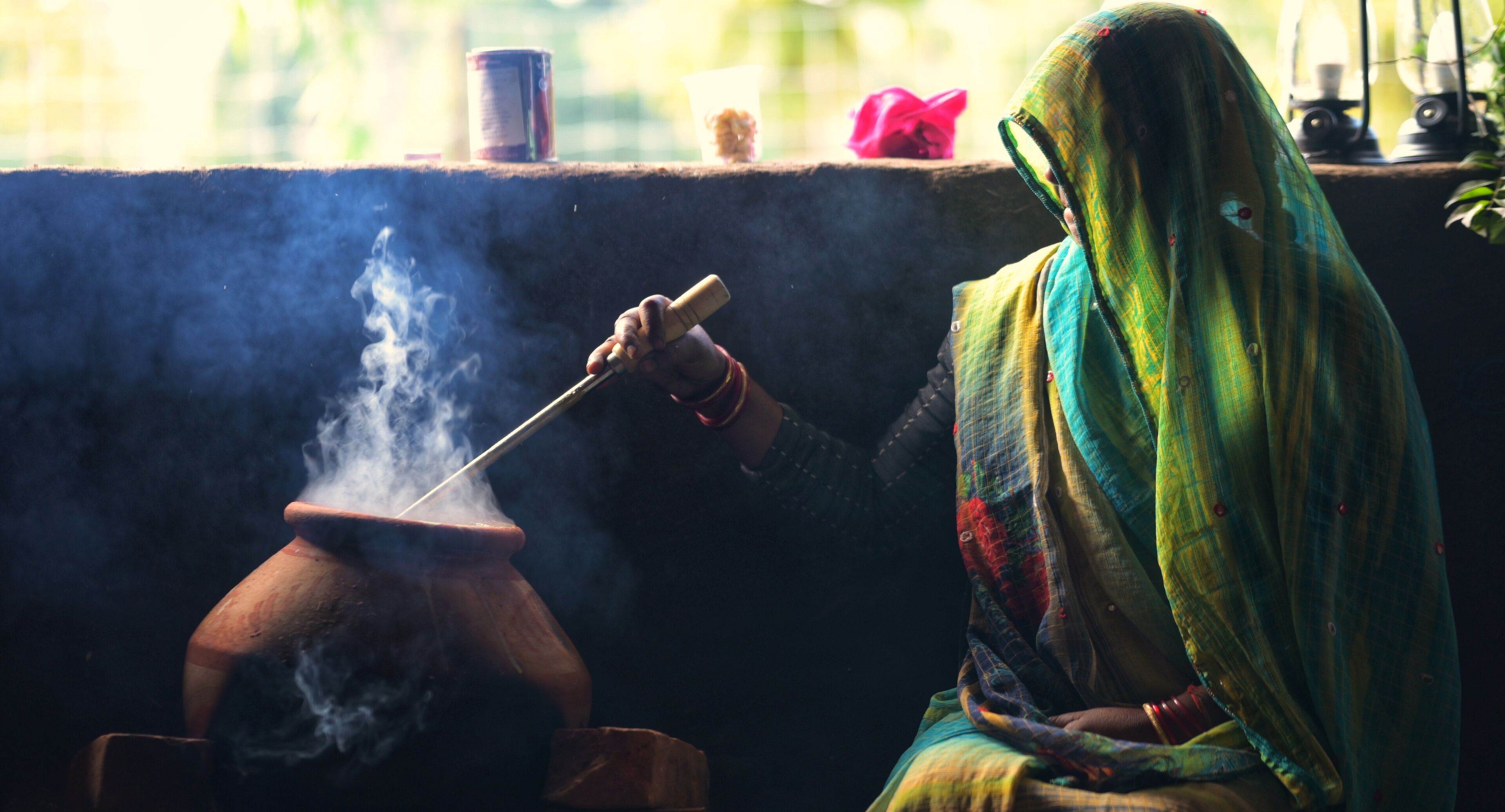 Una persona cocinando en una olla de barro que expulsa vapor.