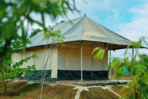 A large, open-sided tent with a peaked roof, surrounded by greenery and a clear sky. -  Bundeli Camps and Resorts, Panna (Panna)