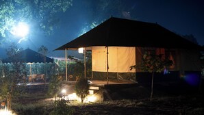 Alojamiento en tienda de campaña con zona de estar al aire libre cubierta y vistas del paisaje circundante.