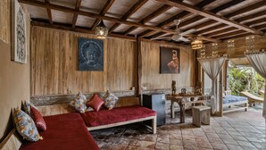A wooden interior with a red sofa, a small table, and a ceiling fan.