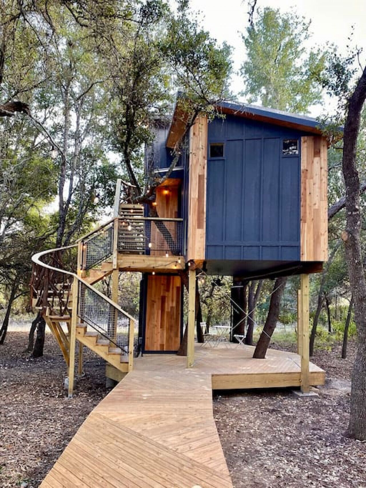 A treehouse with a wooden staircase and a small deck area.