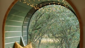 Un coin lecture confortable avec une fenêtre circulaire donnant sur une forêt.