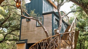 A treehouse with a wooden staircase and a blue exterior.
