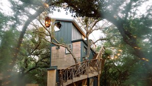 A treehouse with a wooden staircase and a lantern.