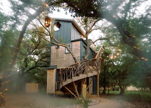 Une cabane dans les arbres avec un escalier en bois et une lanterne.