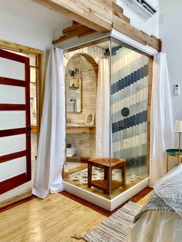 Une salle de bain moderne avec une douche à parois de verre, des poutres en bois et un sol carrelé.