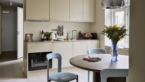A modern kitchen with white cabinets, a dining table with chairs, and a vase with flowers on the table. - One-Bedroom Apartment for 6 with Open Plan (København)