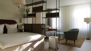 A hotel room with a large bed, a desk, a chair, a suitcase, and a hanging light fixture. - One-Bedroom Apartment for 6 with Open Plan (København)