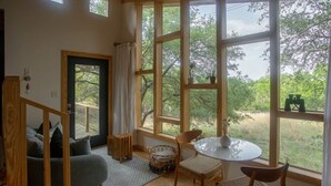 A cozy room with a large window, a round table, a sofa, and a chair. - Sapling Treehouse at HoneyTree (Fredericksburg)