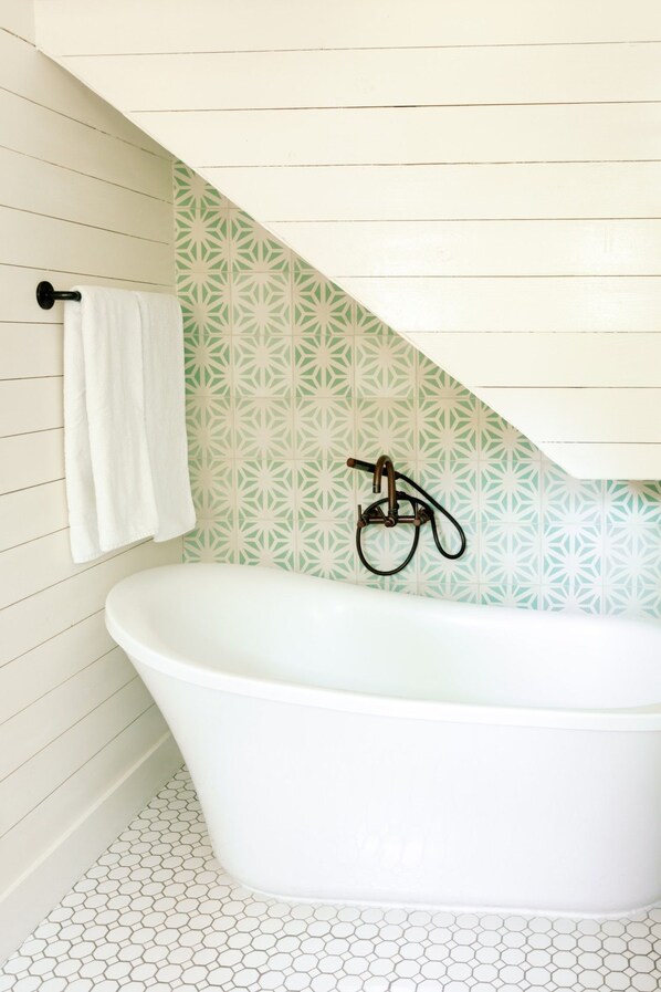 Une salle de bain avec une baignoire sur pieds, un porte-serviettes et des carreaux muraux à motifs.