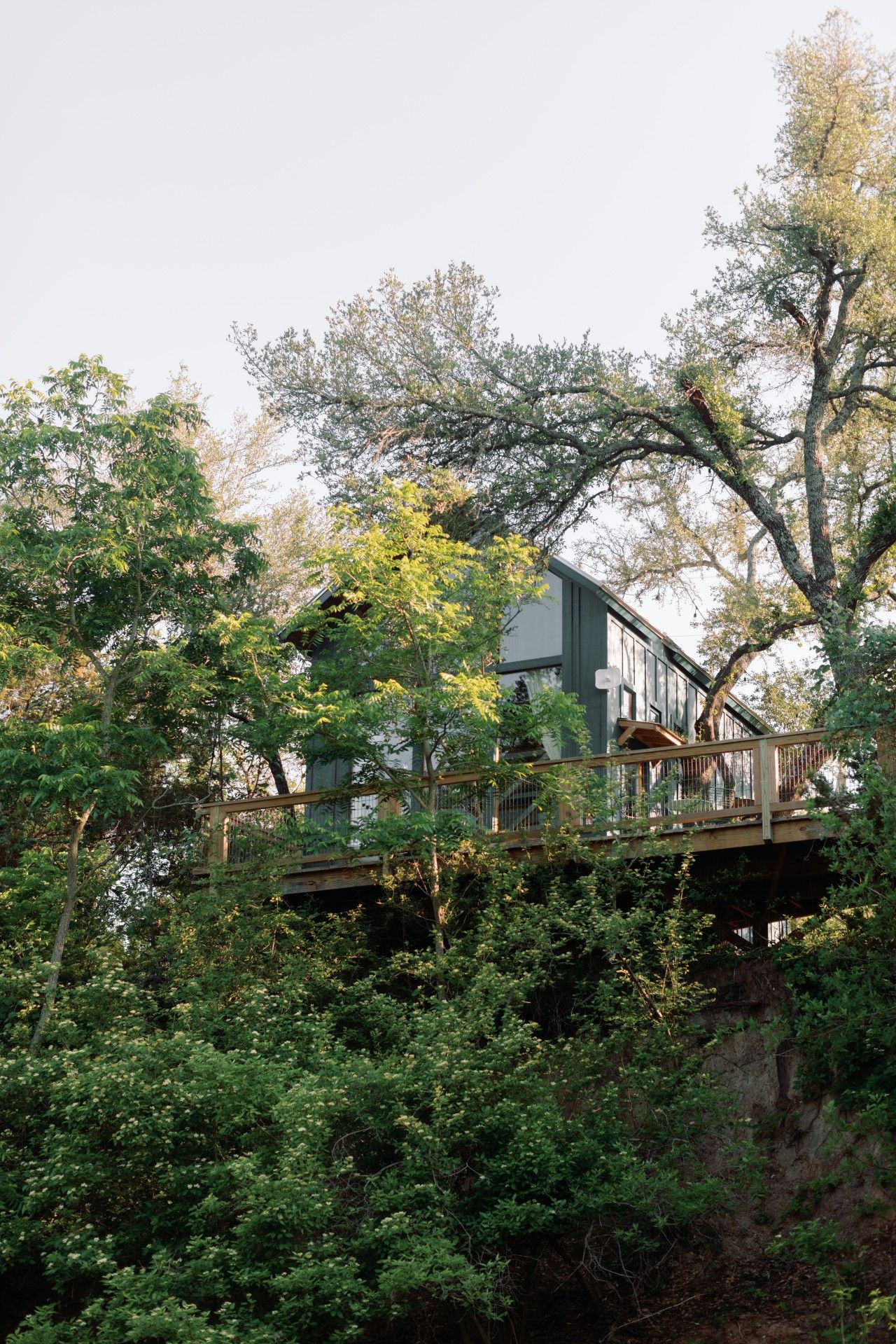 A house with a wooden deck and a staircase leading to a balcony.