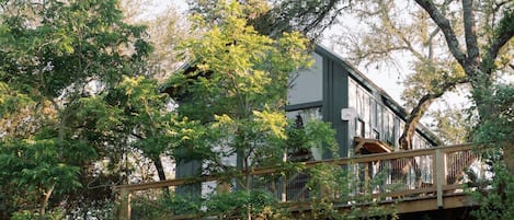 A house with a wooden deck and a staircase leading to a balcony.