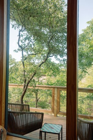 Une terrasse en bois avec vue sur un arbre et une clôture.