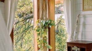 A cozy room with a bed, wooden dresser, and a window with curtains.