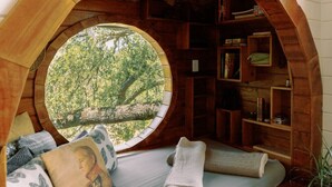 A cozy reading nook with a circular window, wooden bookshelves, and comfortable seating.
