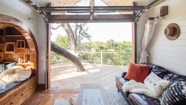 A cozy cabin interior with a wooden deck, a leather sofa, and a rustic wooden shelf.