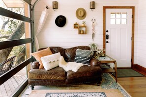 A cozy living room with a brown leather sofa, a wooden coffee table, and a white door.