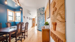 A dining area with a wooden table and chairs, a blue accent wall, and a decorative wall hanging.