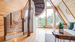 A wooden staircase leading to a loft bedroom with a sloped ceiling and large windows. - Blue Sage No. 2 - The Floating A-Frame (Fredericksburg)