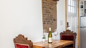 A wooden dining table with two chairs, a bottle of wine, and two glasses. - Blue Sage No. 7 - The Rooftop Soak Tub (Fredericksburg)