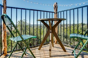 A wooden deck with a metal railing, two green chairs, and a small table.