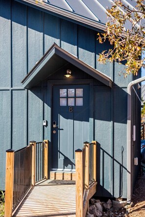 A wooden deck leading to a dark blue door with a small porch and a mailbox.