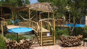 Un espace piscine doté d’une terrasse en bois, d’une piscine et d’un coin salon abrité.