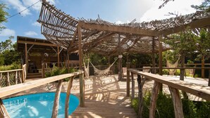 Une terrasse en bois avec une piscine, des pergolas en bois et des hamacs.