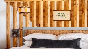 Une pièce aux murs lambrissés, avec un lit, une lampe suspendue et un tableau encadré.