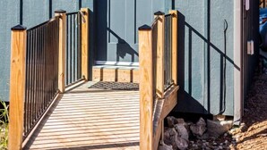 Un bâtiment à l’extérieur d’un bleu foncé, avec un porche en bois doté d’une balustrade noire et une porte agrémentée d’une petite fenêtre.